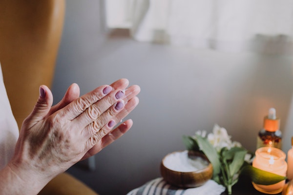Elder woman's hands together in prayer or meditation